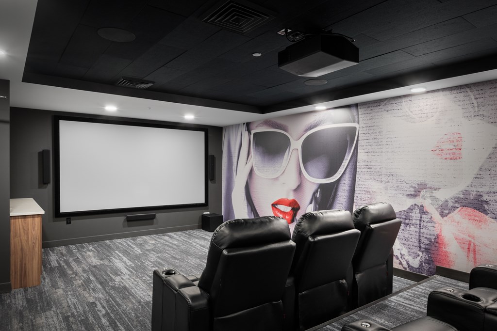 a screening room with black leather chairs and a large mural on the wall